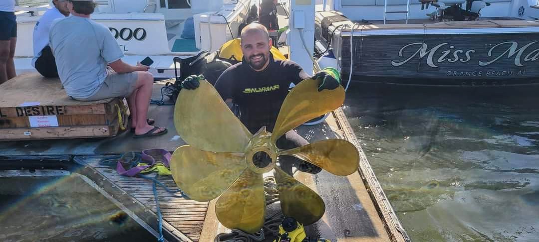 Herstek Diving Service technician with a polished bronze propeller at the dock